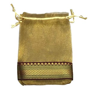 May include: A gold-colored drawstring pouch with a decorative band of gold and maroon. The pouch is made of a sheer, shimmering fabric and is tied with a gold cord.