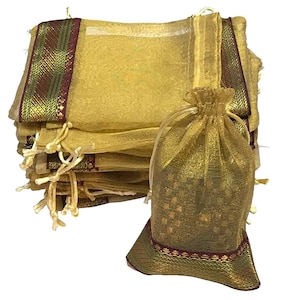 May include: A stack of gold-colored organza drawstring bags with decorative trim in green, gold, and burgundy. One bag is open, revealing a glimpse of its contents. The bags are suitable for small gifts or favors.