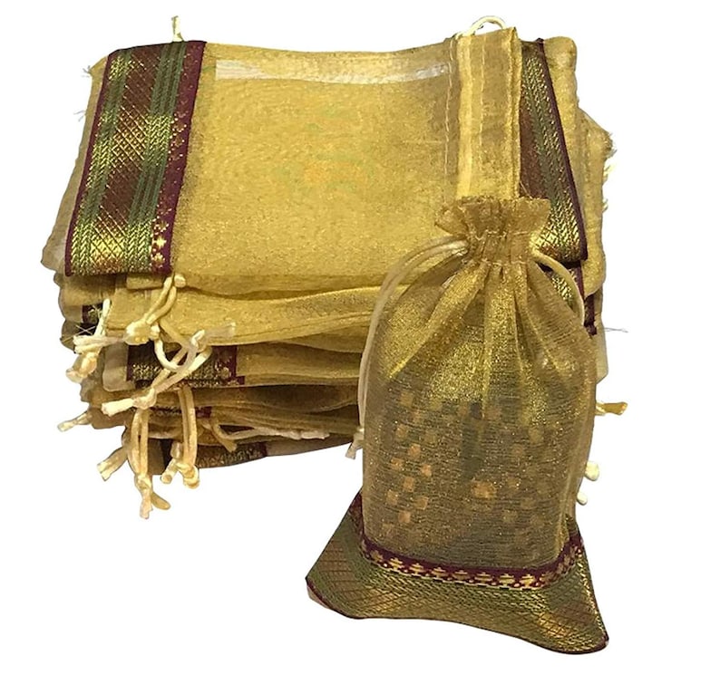 May include: A stack of gold-colored organza drawstring bags with decorative trim in green, gold, and burgundy. One bag is open, revealing a glimpse of its contents. The bags are suitable for small gifts or favors.