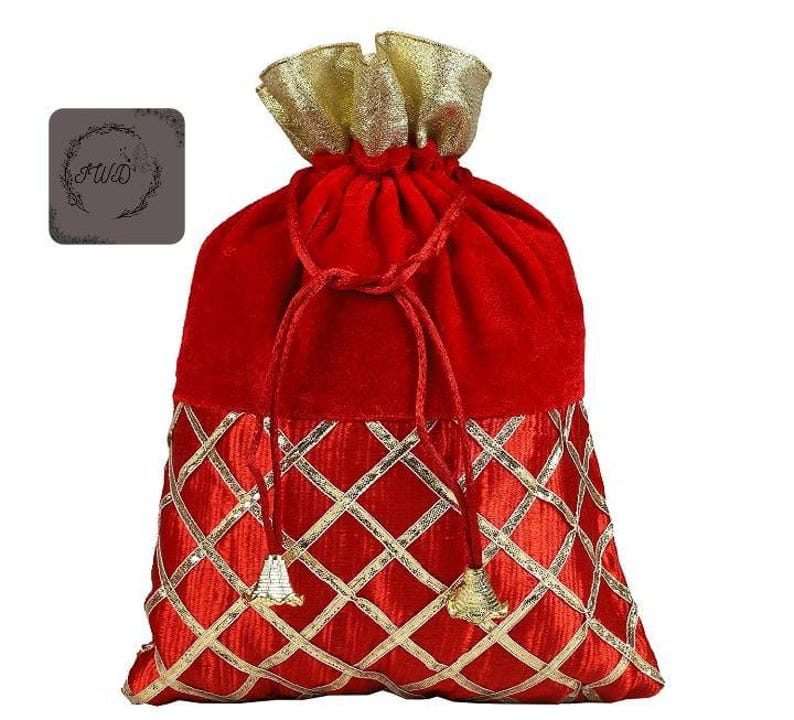 May include: A red velvet drawstring bag with gold accents. The top of the bag is gathered with a gold fabric, and the bottom features a gold diamond pattern. The drawstring is a matching red cord with gold tassels.