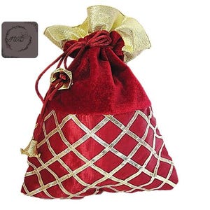 May include: A red velvet drawstring gift bag with gold accents. The bag features a gold diamond pattern on the lower half and a gold ribbon closure. The top is a gold fabric, and the bag has gold tassels.