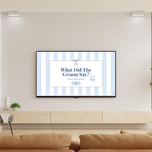 May include: A flat-screen TV displays a game titled "What Did The Groom Say?" against a blue and white striped background. The game is for Emma's Bachelorette party. The TV is mounted on a light wood cabinet in a living room setting.