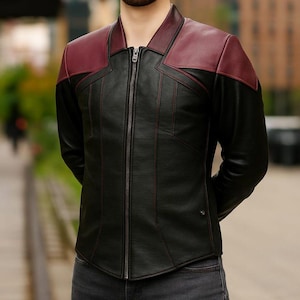 May include: Black leather jacket with a burgundy collar and shoulder panels. The jacket has a front zip and red stitching. A stylish outerwear piece.