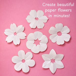Puede incluir: Seis recortes de flores de papel blanco con diversas formas de p&eacute;talos y orificios centrales, dispuestos sobre un fondo rosa. El texto "Create beautiful paper flowers in minutes!" est&aacute; impreso en blanco en la esquina superior derecha.