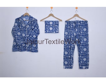 May include: A blue and white floral print pajama set, including a button-down shirt, a matching eye mask, and pants. The set is displayed on wooden hangers against a white background. The text "Jaipur Textile Work" is visible.