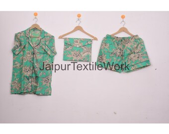 May include: A three-piece pajama set in a teal floral print. The set includes a short-sleeved button-down shirt, matching shorts, and a small pouch. The edges of the shirt and shorts are trimmed with black piping. The text "Jaipur Textile Work" is visible.