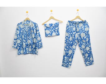 May include: A blue and white floral pajama set, including a button-down shirt, drawstring pants, and a matching pouch. The set is displayed on wooden hangers against a white background. The floral pattern is a repeating design.