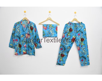 May include: A blue pajama set with a floral pattern, including a button-down shirt, pants, and a small square pouch. The set features red and green floral designs. The text "Jaipur Textile Works" is visible.