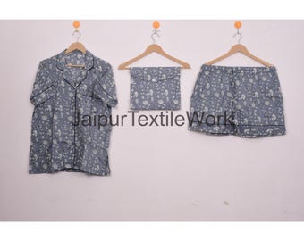May include: A three-piece pajama set in a floral print. The set includes a button-down shirt, shorts, and a matching pouch. The fabric is a muted blue with a white floral pattern and black trim. The text "Jaipur Textile Work" is visible.