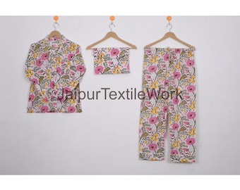 May include: A three-piece floral pajama set. The set includes a button-down shirt, a matching headscarf, and pants. The pajamas are white with a pink and yellow floral pattern. The text "Jaipur Textile Work" is visible.