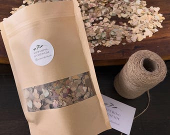 May include: A tan paper pouch with a clear window containing small, multi-coloured heart-shaped paper cutouts. A circular white label on the pouch features the text NIPPERING HANDMADE and an Instagram icon. A spool of jute twine sits nearby.
