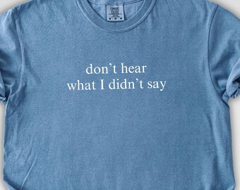 May include: A blue t-shirt with the text "don't hear what I didn't say" in white. The shirt has a crew neck and short sleeves. The fabric appears soft and slightly wrinkled.