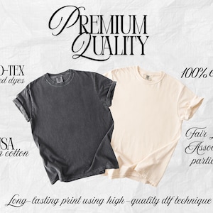 May include: Two short-sleeve crew neck t-shirts, one in charcoal gray and one in cream. Text includes: PREMIUM QUALITY, OEKO-TEX certified dyes, 100% cotton, USA grown cotton, Fair Labor Association participant, and Long-lasting print using high-quality dtf technique.