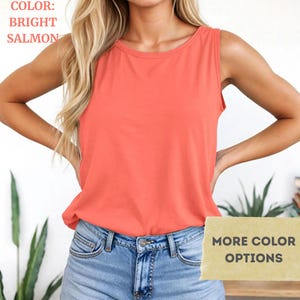 Puede incluir: Una camiseta sin mangas de color salm&oacute;n brillante con cuello redondo, combinada con vaqueros azul claro. La imagen incluye el texto "COLOR: BRIGHT SALMON" en la esquina superior izquierda y "MORE COLOR OPTIONS" en un rect&aacute;ngulo beige abajo.