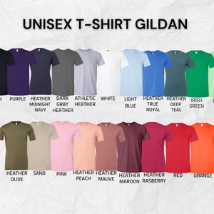 K&ouml;nnte beinhalten: Eine Auswahl an Gildan Unisex-T-Shirts in verschiedenen Farben, darunter Schwarz, Lila, Heather Navy, Dunkelgrau, Athletic Heather, Wei&szlig;, Hellblau, Heather Royal, Deep Teal, Irish Green und Mint. Weitere Farben sind Heather Olive, Sand, Pink, Heather Peach, Heather Mauve, Heather Maroon, Heather Raspberry, Rot und Orange.