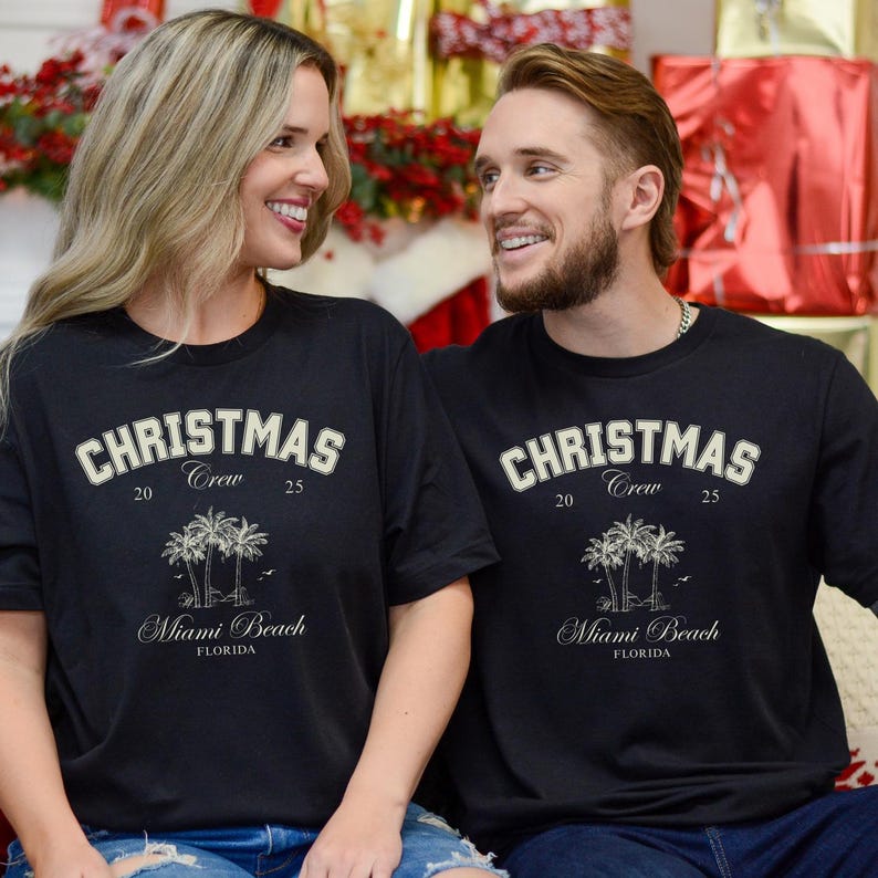 May include: A black short-sleeved t-shirt featuring the text CHRISTMAS CREW 20 25, an illustration of three palm trees, and the text Miami Beach FLORIDA in a light-colored font. The design is centered on the chest of the garment.