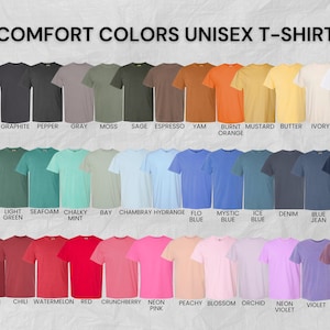 May include: A color chart displaying Comfort Colors unisex t-shirts in forty-two distinct shades, arranged in three rows. Each shirt is labeled with its specific color name, ranging from black, gray, and earth tones to vibrant blues, reds, and pinks.