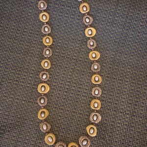 K&ouml;nnte beinhalten: Eine silber- und goldfarbene Halskette mit ovalen und kreisf&ouml;rmigen Gliedern. Die Halskette hat einen Kettenverschluss und abwechselnd goldfarbene ovale Glieder mit silberfarbenen kreisf&ouml;rmigen Gliedern. Jedes Glied hat eine kleine, wei&szlig;e, perlenartige Perle in der Mitte.