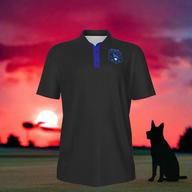 Puede incluir: Polo negro con cuello y botones azules, con un emblema azul en el pecho. La camisa est&aacute; colocada contra un fondo de puesta de sol con la silueta de un perro en primer plano.