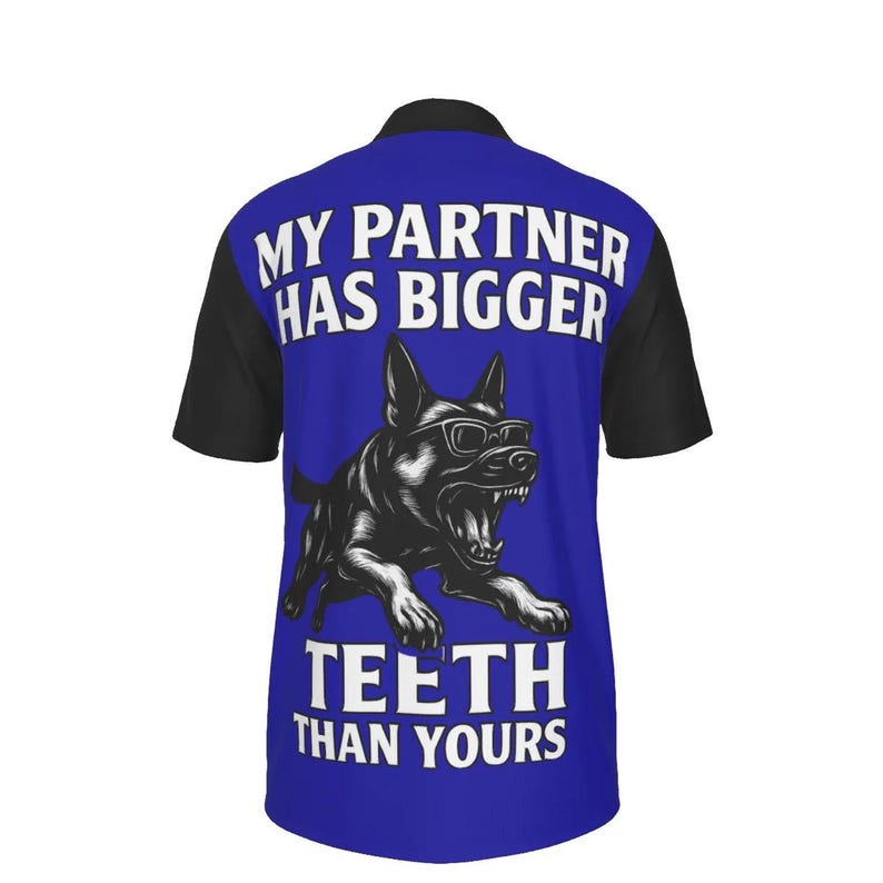 Puede incluir: Polo azul con mangas negras. Presenta un gr&aacute;fico de un perro con gafas y el texto "MY PARTNER HAS BIGGER TEETH THAN YOURS" en blanco. La camisa tiene un cuello cl&aacute;sico y mangas cortas.