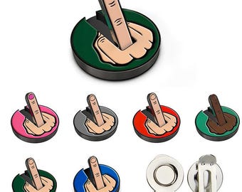 Può includere: Una collezione di segnapunti da golf con una mano che fa il gesto del dito medio. I segnapunti hanno una base rotonda in vari colori, tra cui verde, rosa, rosso e blu. La mano è raffigurata con il dito medio alzato.