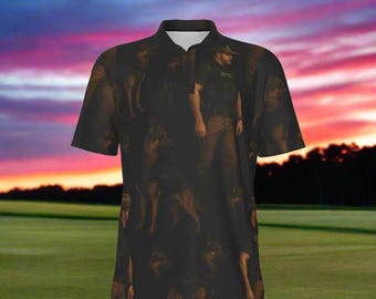 Peut inclure: Polo noir avec un motif répété d'un homme et de chiens. La chemise a un col blanc et une patte de boutonnage. L'arrière-plan montre un coucher de soleil sur un champ vert.