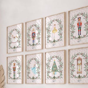 May include: Eight framed watercolor prints featuring Christmas-themed illustrations. The prints depict a nutcracker, angel, ballerina, Christmas tree, and a grandfather clock, each surrounded by a wreath of greenery and berries. The frames are light wood.