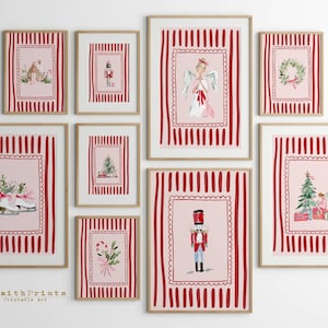 May include: A collection of framed Christmas-themed art prints. Each print features a pink background with a red striped border. The prints depict various holiday images, including a nutcracker, angel, and Christmas tree. The frames are a light brown color.