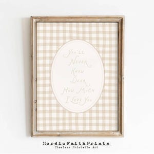 May include: Framed wall art with a beige and white gingham pattern background. An oval shape in the center contains the handwritten text, "You'll Never Know Dear How Much I Love You." The frame is a light brown color.