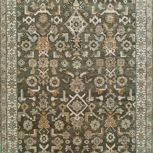 May include: A rectangular area rug with an intricate floral pattern in shades of olive green, beige, and gold. The rug features a detailed border with geometric and floral motifs. The design is symmetrical, with a central medallion and repeating patterns.