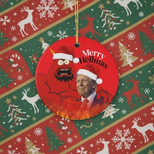 以下が含まれることがあります： 「Merry Hellmas」の文字が入った赤い丸いクリスマスオーナメント。漫画の悪魔とサンタ帽をかぶった男性が描かれています。背景はトナカイと雪の結晶の入ったお祝いのクリスマス模様です。