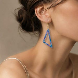 Geometriska örhängen med hänge i konstgalleriet - minimalistiska blå triangelformade accessoarer - abstrakta konstsmycken för utställningsdatum och eleganta outfits