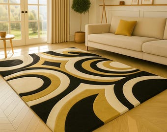 Op de afbeelding: Een groot, rechthoekig vloerkleed met een opvallend geometrisch patroon. Het kleed heeft een zwarte achtergrond met crème, goud en zwarte gebogen vormen. Het ligt op een houten vloer in een woonkamer.