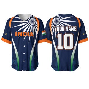 Pode incluir: Uma camisola de basebol azul-marinho com detalhes em laranja, um design de raios de sol em branco e o texto INDIA na frente. As costas exibem o texto YOUR NAME acima do número 10 em branco com contornos laranja e uma pequena bandeira.