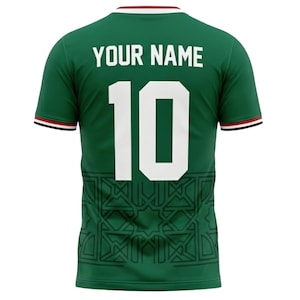 May include: Green soccer jersey with the number 10 in white. The jersey has the text "YOUR NAME" above the number. The jersey has a geometric pattern at the bottom and red and black trim on the sleeves and collar.