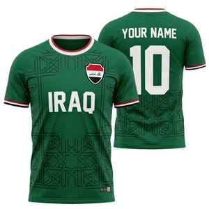 May include: Green soccer jersey with the word "IRAQ" in white block letters. The jersey has a white and red trim on the collar and sleeves. The number "10" is on the back, with the words "YOUR NAME" above it.