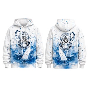 Puede incluir: Una sudadera con capucha blanca que presenta un estampado gráfico de un tigre blanco caminando sobre agua azul. El diseño incluye salpicaduras de pintura azul en la tela, una capucha con cordón, mangas largas y puños acanalados.