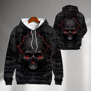 May include: Black hoodie with a skull design. The skull has red eyes and a red outline. The hoodie is displayed on a wooden hanger. The back of the hoodie is also visible, showing the same skull design.
