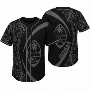Könnte beinhalten: Ein schwarzes Baseballtrikot mit dunkelgrauem Stammesmuster und dem Siegel von Guam, das eine Palme und ein Boot zeigt. Die Vorderseite hat eine Knopfleiste mit grauer Paspelierung, während auf der Rückseite das Wort GUAM in großen grauen Buchstaben steht.