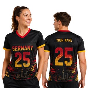 May include: A black V-neck jersey featuring the word GERMANY and the number 25 in a red and yellow pixelated gradient. The design includes a skyline graphic at the bottom. The back displays the text YOUR NAME above the number 25 in the same style.