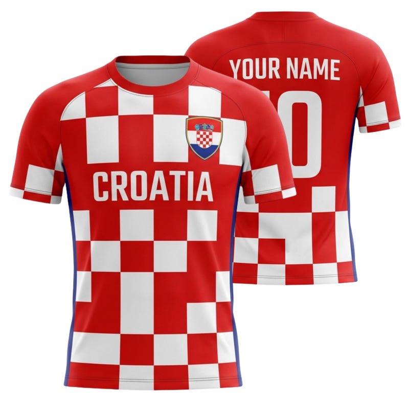 Puede incluir: Una camiseta de f&uacute;tbol de Croacia a cuadros rojos y blancos con la palabra "CROATIA" en el pecho y el escudo de armas croata. La parte trasera de la camiseta es roja con el texto "YOUR NAME" y el n&uacute;mero "0".