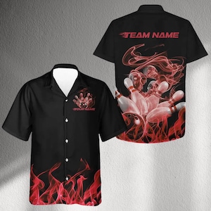 Puede incluir: Camisa de bolos negra con un diseño de llamas rojas en la parte inferior y un gráfico de bola y bolos. La camisa tiene el texto "YOUR NAME" y "TEAM NAME" en rojo. La parte trasera de la camisa presenta un gráfico de bolos y calaveras.