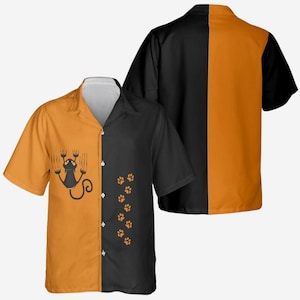 May include: Short-sleeved button-up shirt with a split design. One side is orange with a black cat graphic, the other is black with orange paw prints. The back of the shirt is split black and orange.
