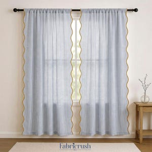 Puede incluir: Dos cortinas transparentes azul claro con un patrón de rayas verticales y un ribete dorado ondulado. Las cortinas cuelgan de una barra negra frente a una ventana. La marca "Fabricrush USA" es visible en la parte inferior.