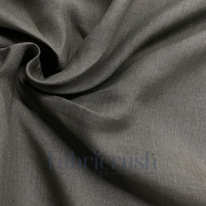 May include: Close-up of a dark gray linen fabric with visible texture and folds. The fabric has a subtle sheen and appears soft. The image highlights the natural weave and color variations of the material, suitable for apparel or home decor.