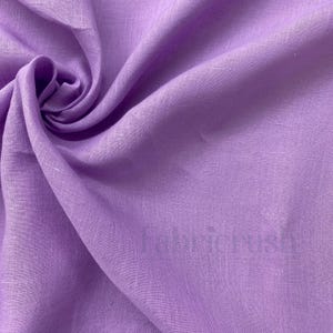 May include: A close-up of a lavender-colored fabric with visible texture and folds. The fabric is a solid color and appears to be linen or a similar material. The word "Fabricrush" is faintly visible on the fabric.