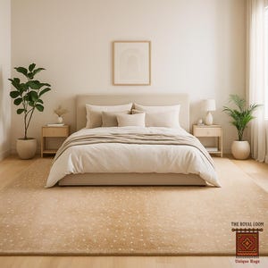 May include: A bedroom scene featuring a beige bed with a neutral-toned comforter and pillows. A large, patterned rug in shades of beige and tan covers the floor. Two nightstands flank the bed, each with a lamp and a potted plant. A framed artwork hangs above the bed.