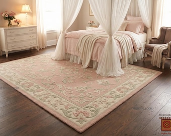 May include: A large, rectangular pink rug with a floral design and a cream-colored border. The rug is placed in a bedroom with a bed, curtains, and a dresser. The rug's dimensions are approximately 8 x 10 feet.