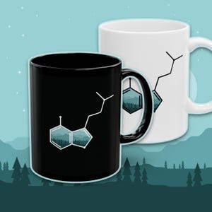 May include: Two ceramic mugs, one black and one white, each featuring a molecular structure design with a forest scene inside the geometric shapes. The black mug has a black handle, while the white mug has a white handle. The background is a teal color with a forest silhouette.