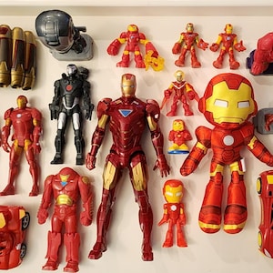 May include: A collection of Iron Man toys and figurines in various sizes and styles. The toys are primarily red and gold, with some black and silver accents. Includes action figures, a plush toy, and a toy car.